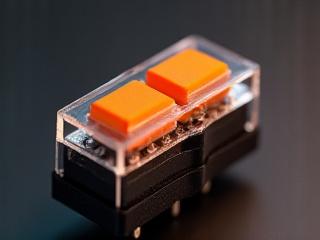 Macro shot of a Holy Panda tactile switch, showcasing its unique orange stem and clear housing.